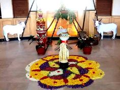 an arrangement of flowers and statues in the middle of a room with two white goats standing next to each other