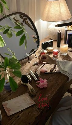 a table topped with lots of makeup and other items next to a mirror on top of a wooden table