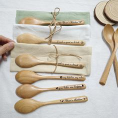 six wooden spoons and two tea towels with words on them