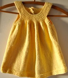 a yellow knitted dress hanging on a wooden hanger next to a white wall