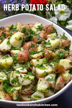 a white bowl filled with potatoes and parsley on top of a blue table cloth