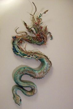 two dragon sculptures on the wall next to each other, one with its tail curled up