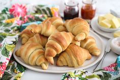 several croissants on a plate with butter and sauces in the background