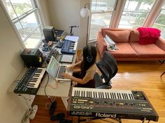 a woman sitting at a desk with an electronic keyboard and music equipment in front of her