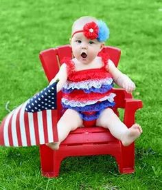 a baby sitting in a red chair with an american flag on it