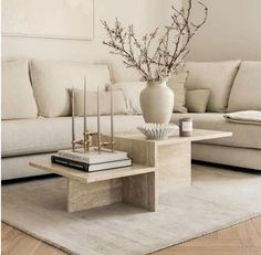 a living room with a couch, coffee table and vase on top of the table