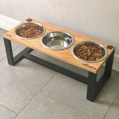 two metal bowls with food in them on a wooden table next to a white wall