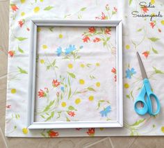 a pair of scissors sitting on top of a table next to a picture frame with flowers