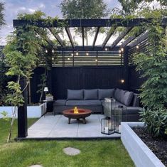 an outdoor living area with couches, tables and lights in the middle of it