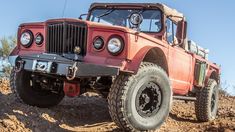 an old red jeep is parked in the dirt