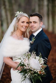 a bride and groom posing for a photo in the woods