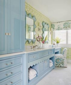 a bathroom with blue cabinets and floral wallpaper on the walls, along with white towels