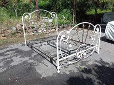 a white metal bed frame sitting on top of a parking lot