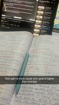 an open notebook with writing on it next to a computer monitor and keyboard, which reads your pain is more cause your goal is higher than average