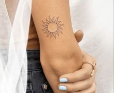 a woman's arm with a small sun tattoo on the left side of her arm