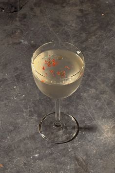 a martini glass filled with white wine and garnished with orange sprinkles