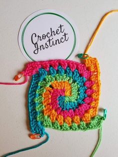 there is a crocheted square with a name tag attached to it and some yarn