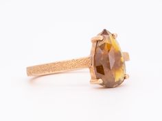 a fancy ring with a pear shaped brown diamond in it's center, on a white background