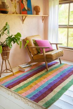 a room with a chair, rug and potted plant