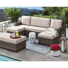 a couch and ottoman on a patio next to a pool