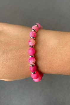 This is a pink beaded bracelet featuring a variety of round beads with different textures and shades of pink. The beads are separated by small silver spacer beads, adding a touch of contrast and elegance. The bracelet is elastic, allowing for a comfortable and adjustable fit on the wrist. The vibrant pink color and unique patterns make it a stylish accessory suitable for casual or dressy occasions. Pink Beaded Earrings, Pink Beaded Bracelet, Pink Beaded Bracelets, Pink Beads, Different Textures, Casual Denim, Faceted Bead, Stylish Accessories, Spacer Beads