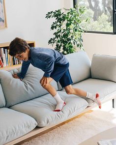 a young boy is jumping on the couch