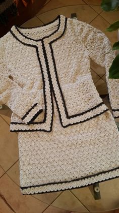 a white crocheted jacket sitting on top of a table next to a potted plant