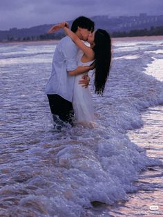 a man and woman kissing in the ocean