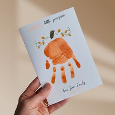 a person holding up a card with an orange handprint on it