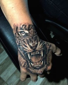 a hand with a tiger tattoo on it's left arm and the face of a tiger