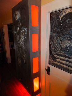 an art piece is lit up in front of a door with red light coming from it