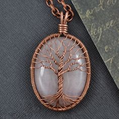 a wire wrapped pendant with a tree of life in the center on a black surface