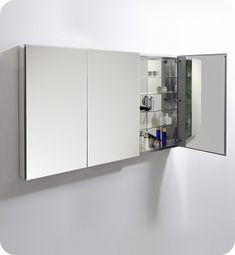 a mirror that is on the side of a wall next to a sink and cabinets