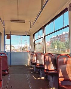 the inside of a bus with empty seats and no people on it, looking out the window