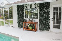 a house that has some plants on the wall and a table in front of it