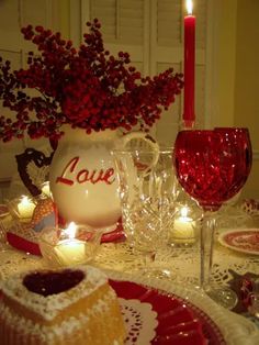 a table set for valentine's day with cake and candles