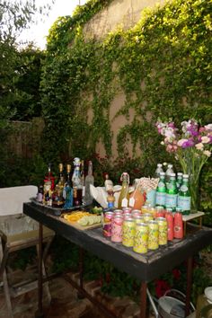 an outdoor table with drinks and condiments on it in front of a wall