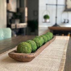 a wooden bowl filled with broccoli sitting on top of a table next to a rug