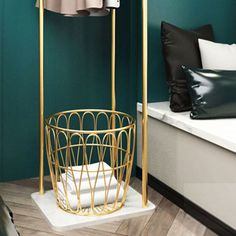 a bathroom with green walls and white counter top, gold metal basket on the floor