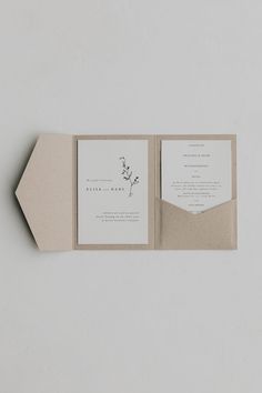 an open pocketfold wedding card on top of a white envelope