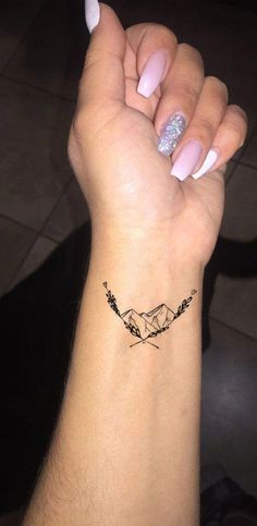 a woman's arm with a small tattoo on the wrist and an arrow in the middle