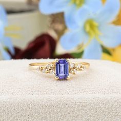 a ring with an amethorate and diamond set in front of blue flowers