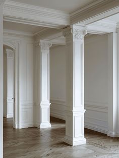 an empty room with white columns and wood floors