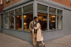 a man and woman standing next to each other in front of a building with windows