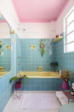 a bathroom with blue tiles and pink walls, including a bathtub in the center