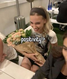 a woman sitting on a bench with flowers in her hand and the caption reads positivity