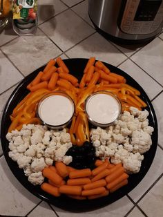 a plate with carrots, cauliflower and crackers in the shape of a face