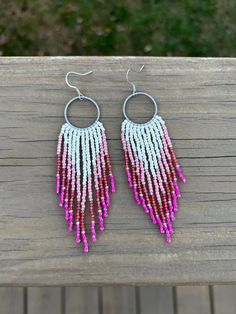 two pairs of pink and white beaded earrings sitting on top of a wooden table