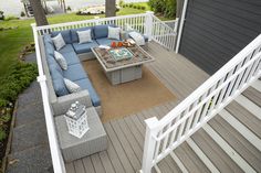 an outdoor living area with couches, tables and chairs on a deck overlooking the water