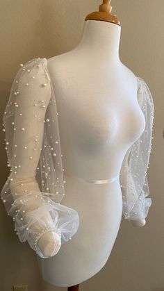 a white mannequin with sheer sleeves and pearls